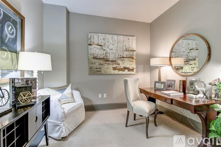 A well-lit room with a desk, chair, and a large painting on the wall.