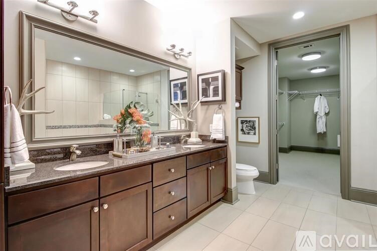 A bathroom with a large mirror, a sink, and a toilet.