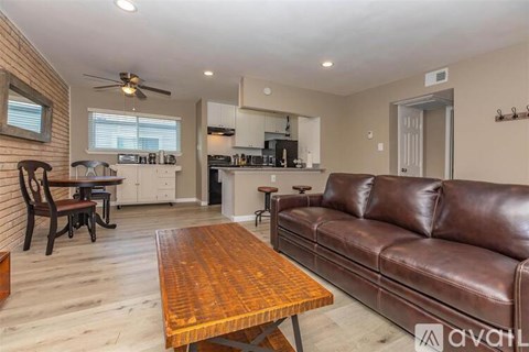 A living room with a brown leather couch and a wooden table.