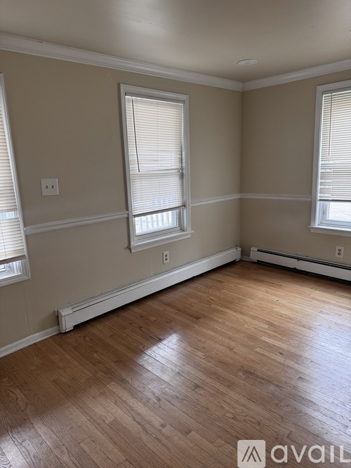 A room with wooden floors and two windows.