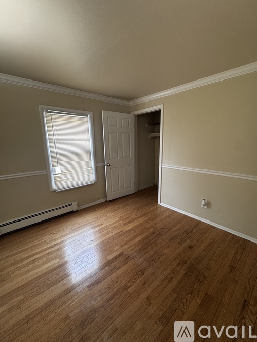 A room with wooden floors and a window with blinds.
