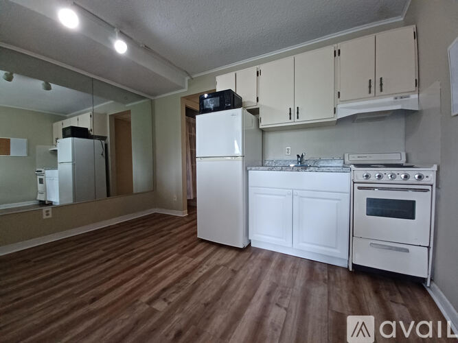A kitchen with white appliances and wooden floors.