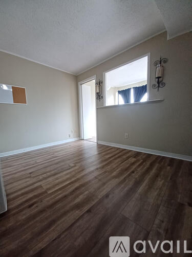 A room with wooden flooring and a window with blinds.