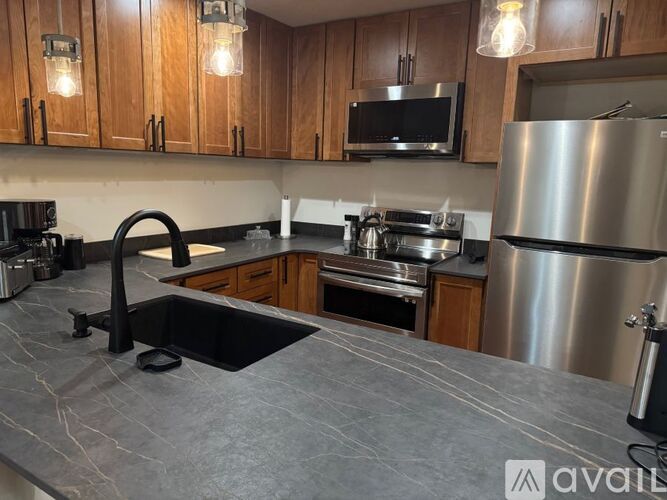 A kitchen with wooden cabinets and a black refrigerator.