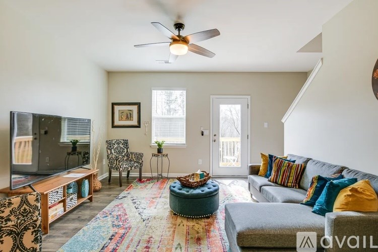 A living room with a grey couch, a wooden entertainment unit, and a rug.