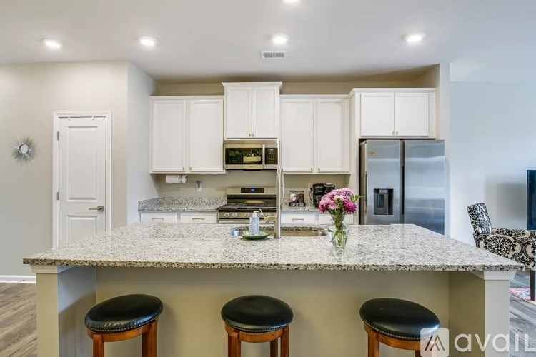 A kitchen with a granite countertop and bar stools.