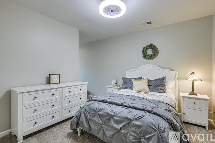 A bedroom with a bed, nightstand, and a wreath on the wall.