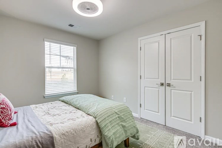 A bedroom with a bed, two pillows, a window, and a ceiling light.