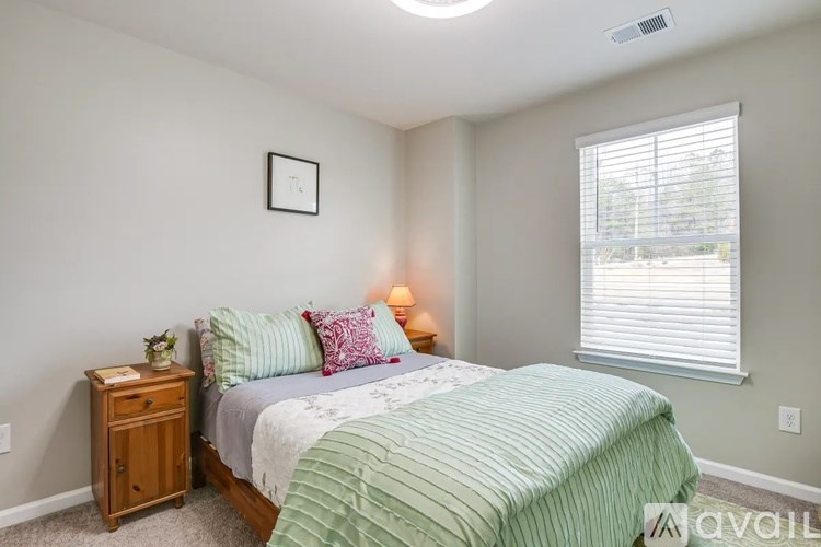 A bedroom with a bed, nightstand, and window.