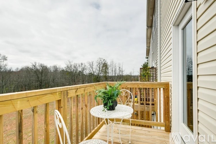 A balcony with a table and chairs overlooking a wooded area.