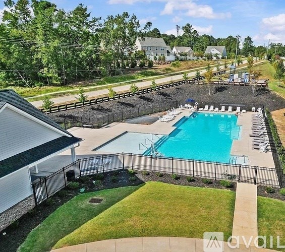 A pool surrounded by a black fence with a house in the background.