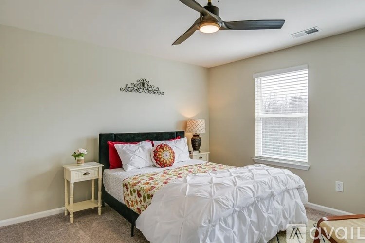 A bedroom with a bed, a fan, and a window.