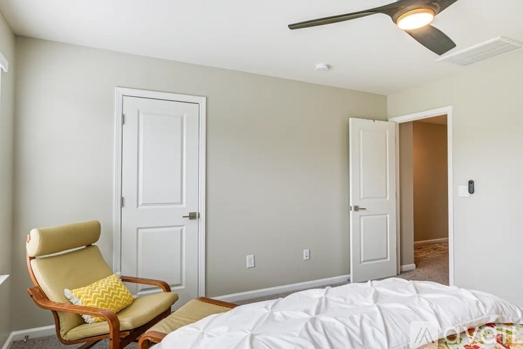 A bedroom with a bed, chair, and two doors.