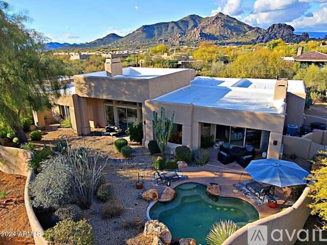 A house with a pool in the foreground and mountains in the background.