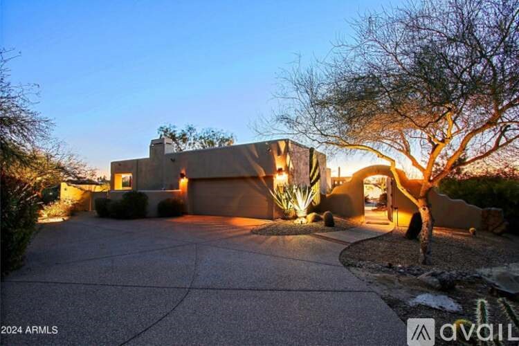 A house with a driveway and a tree in front of it.