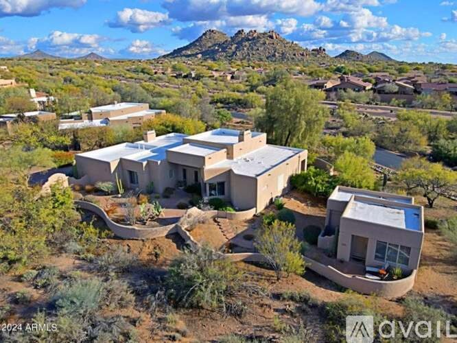 A house in a desert landscape with mountains in the background.