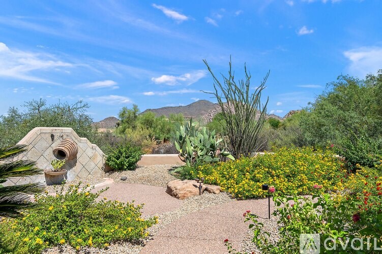 A garden with a stone sculpture and flowering plants.