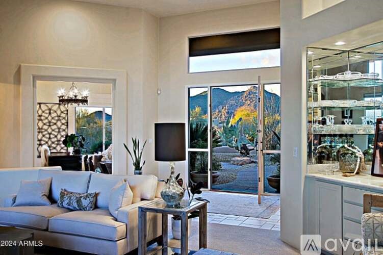 A living room with a couch, a coffee table, and a large window with a view of the mountains.