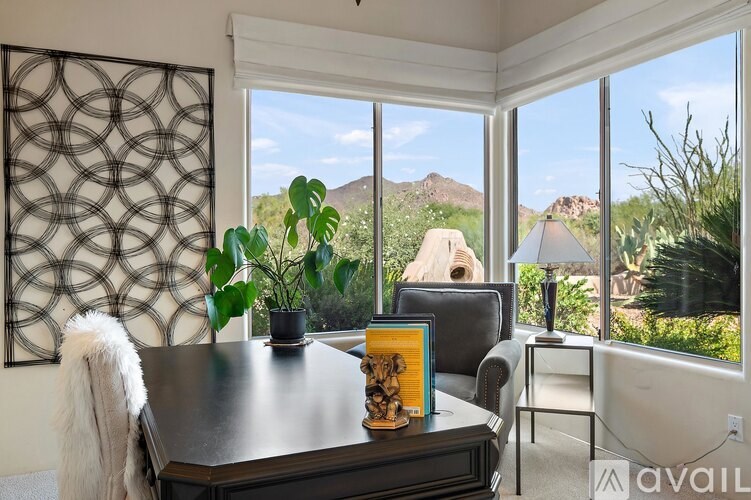 A living room with a table, chairs, and a view of the outdoors through large windows.