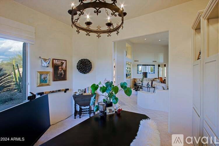 A chandelier hangs over a table in a spacious room.