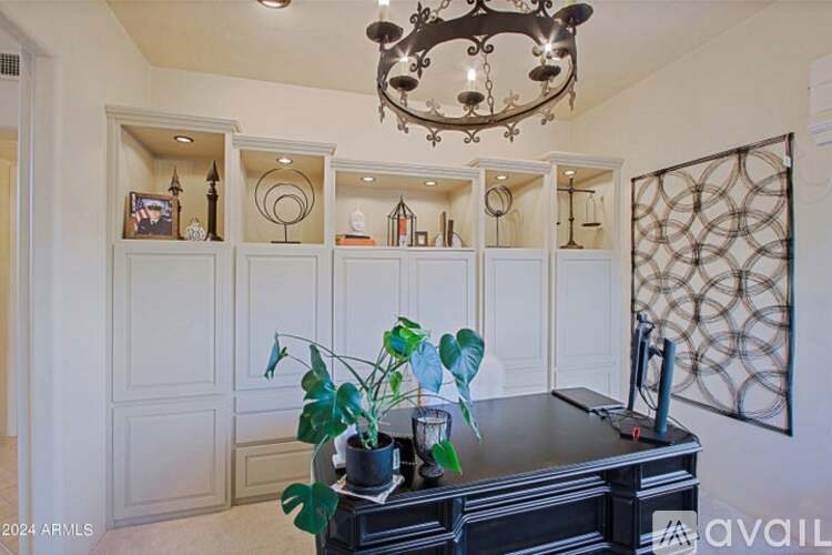 A room with a chandelier, a piano, and a plant on a table.