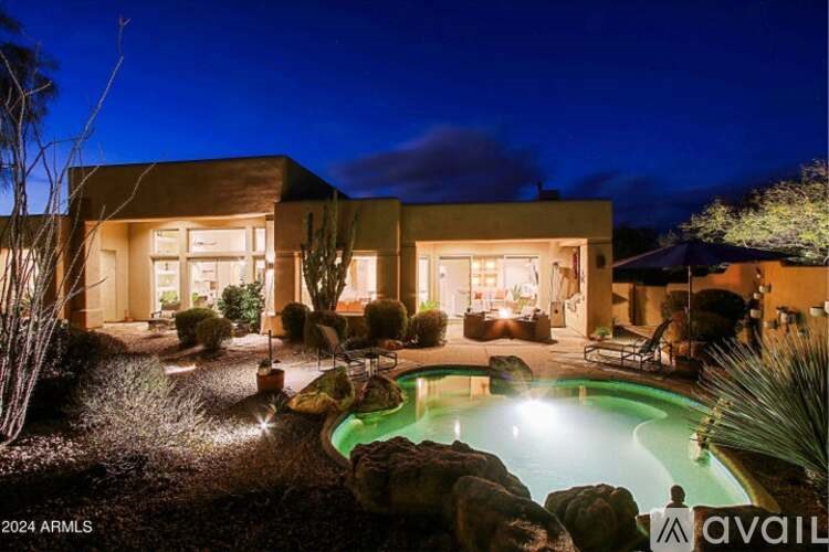 A house with a pool in the backyard at night.