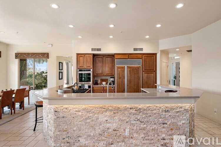 A kitchen with a stone counter top and wooden cabinets.