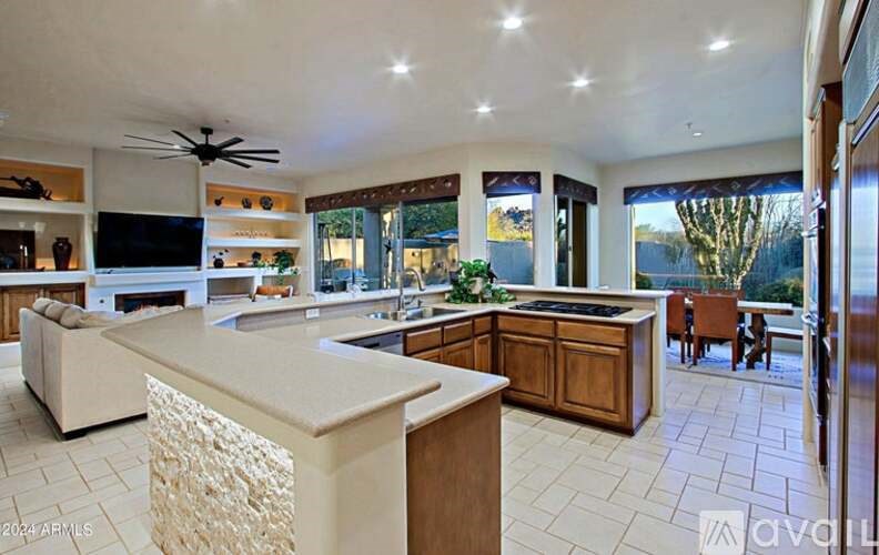 A modern kitchen with a central island and a television above the counter.