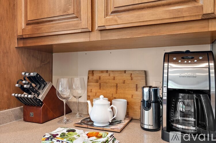 A kitchen counter with a coffee maker, a knife block, and a tea kettle.