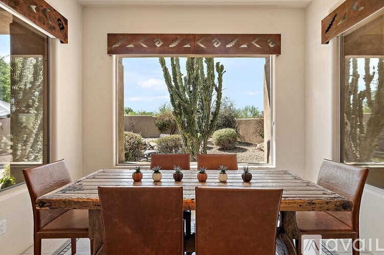A wooden table with chairs and a cactus in the background.