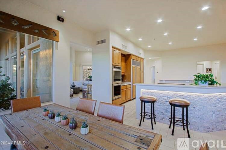 A modern kitchen with a wooden table and bar stools.
