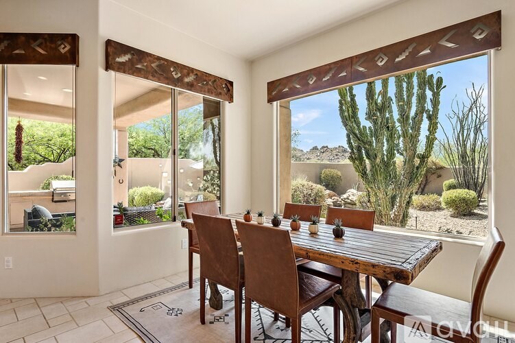 A dining room with a table and chairs with a view of the desert outside.