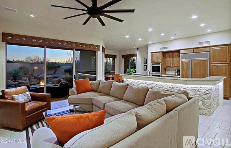 A living room with a large sectional sofa and a ceiling fan.