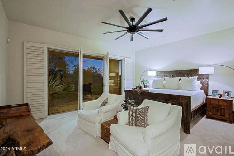 A bedroom with a bed, a couch, and a ceiling fan.