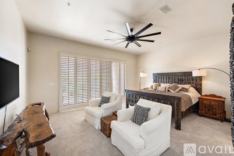 A bedroom with a bed, a chair, and a fan.