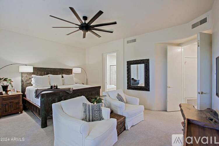 A bedroom with a large bed and a ceiling fan.