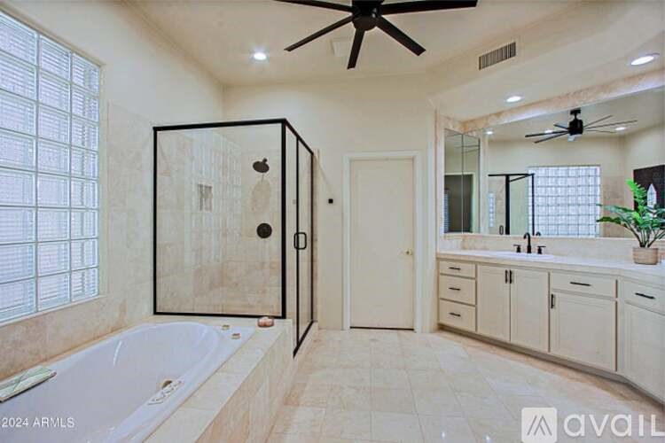 A bathroom with a tub, sink, and a ceiling fan.