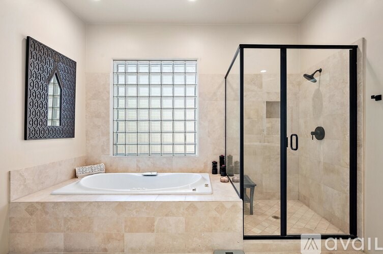 A bathroom with a glass shower door and a bathtub.
