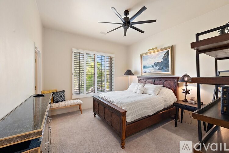 A bedroom with a large bed, a bench, and a painting on the wall.