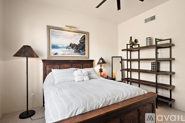 A bedroom with a large bed and a painting on the wall.