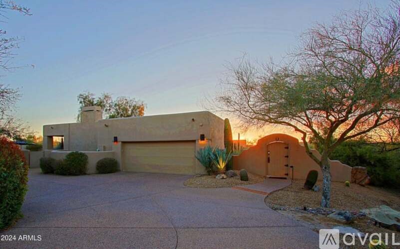 A house with a driveway and a tree in front of it.