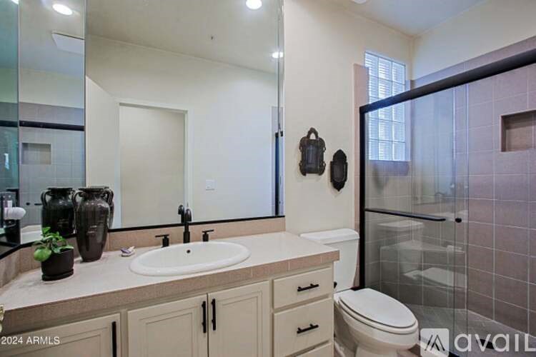 A bathroom with a sink, toilet, and a mirror.