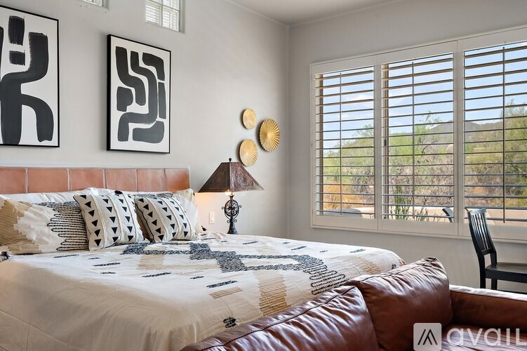 A bedroom with a bed, a chair, and two wall art pieces.