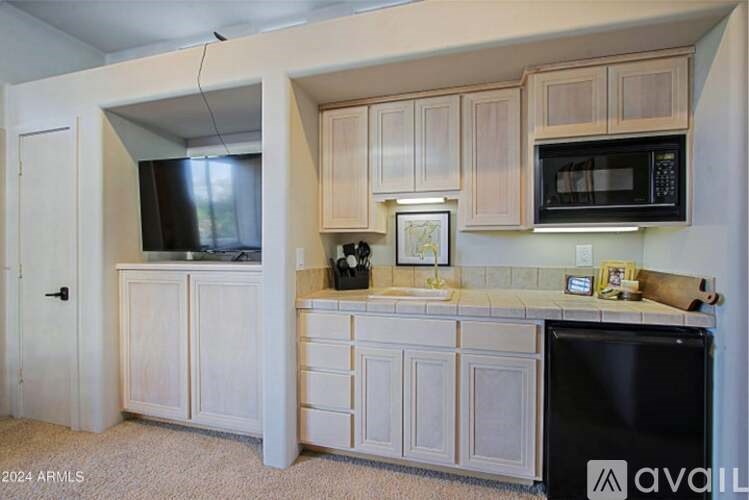 A kitchen with white cabinets and a black fridge.
