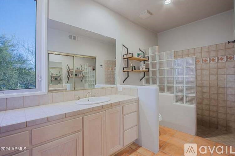A bathroom with a large mirror, a sink, and a shower area.