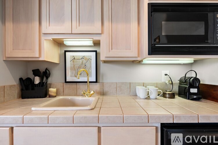 A kitchen with a sink, microwave, and a picture on the wall.