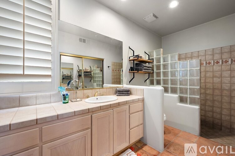 A bathroom with a sink, mirror, and a shower.