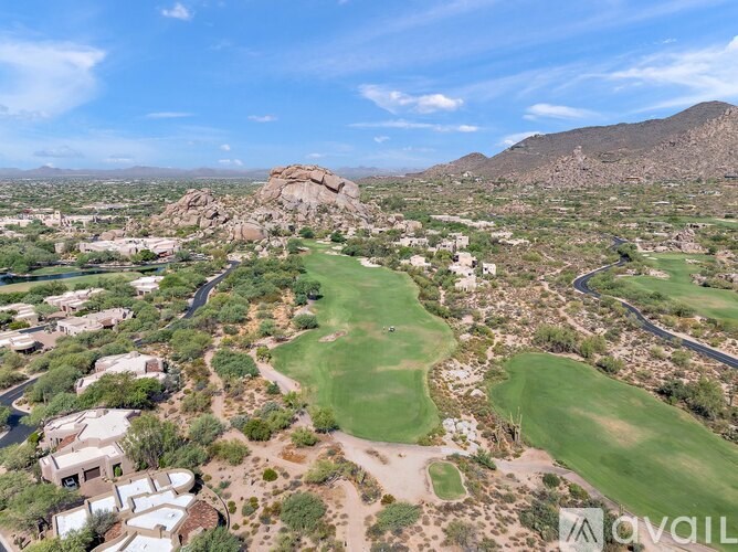 A golf course surrounded by houses and mountains.