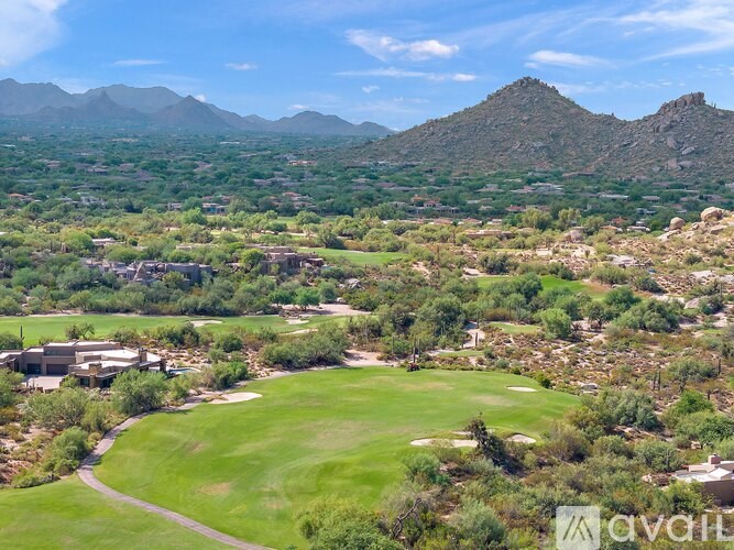 A golf course surrounded by mountains and houses.