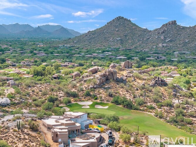 A golf course surrounded by rocky hills and houses.
